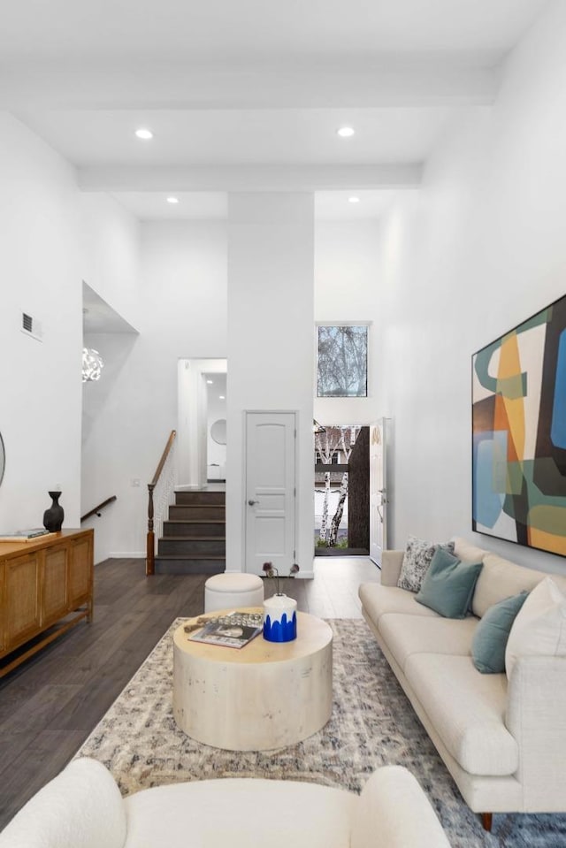 living room featuring beamed ceiling, dark wood-type flooring, and a towering ceiling