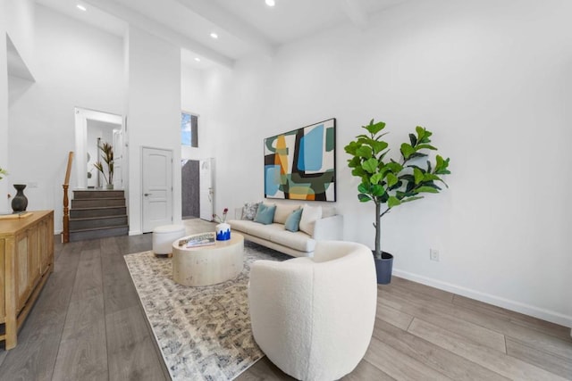 living room featuring hardwood / wood-style flooring, a high ceiling, and beamed ceiling