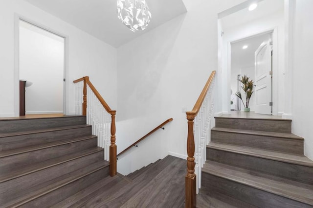 stairs with hardwood / wood-style floors and a notable chandelier