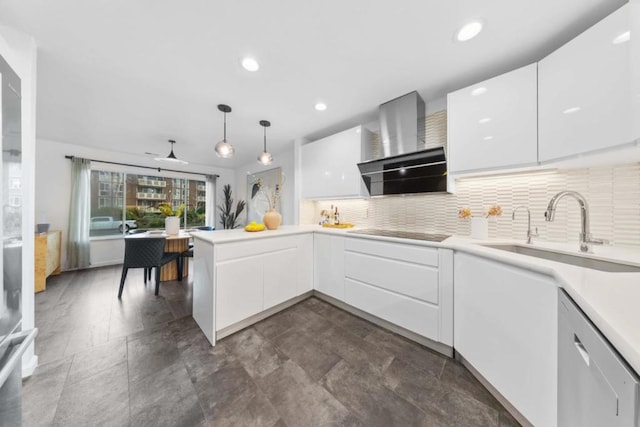 kitchen with pendant lighting, sink, white cabinets, decorative backsplash, and wall chimney range hood