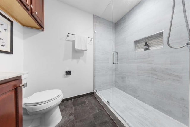 bathroom featuring an enclosed shower, vanity, tile patterned flooring, and toilet