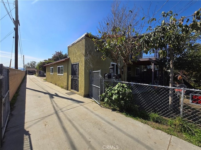 view of home's exterior with a gate, fence, and stucco siding