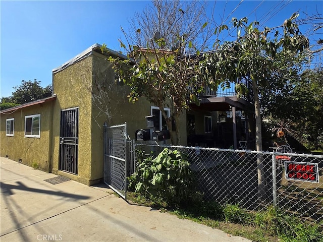 view of front facade with stucco siding, fence, and a gate