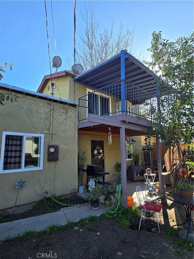 back of house with a patio area, stucco siding, and a balcony