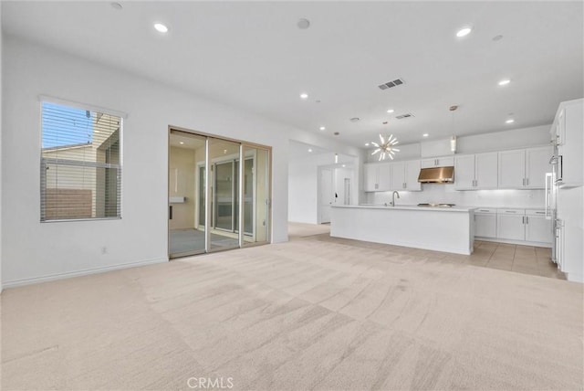 unfurnished living room with sink and light colored carpet