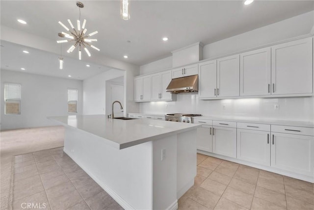 kitchen featuring stove, a large island with sink, sink, and white cabinets