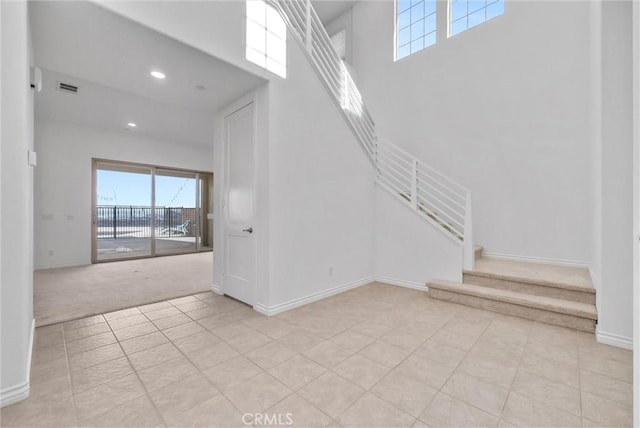 stairway with tile patterned floors and a high ceiling