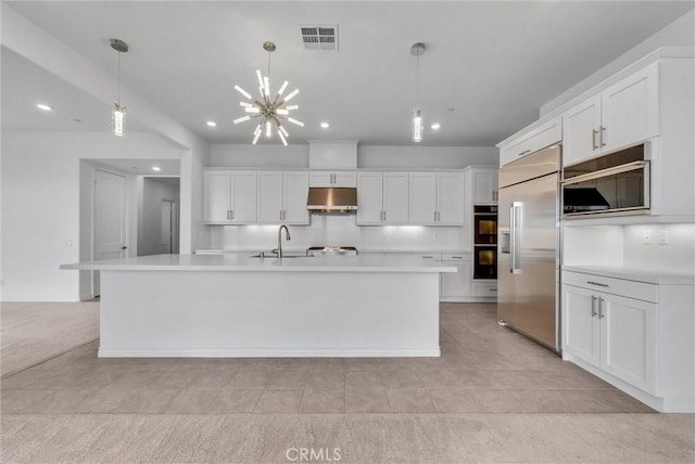 kitchen featuring a kitchen island with sink, hanging light fixtures, white cabinets, and built in refrigerator