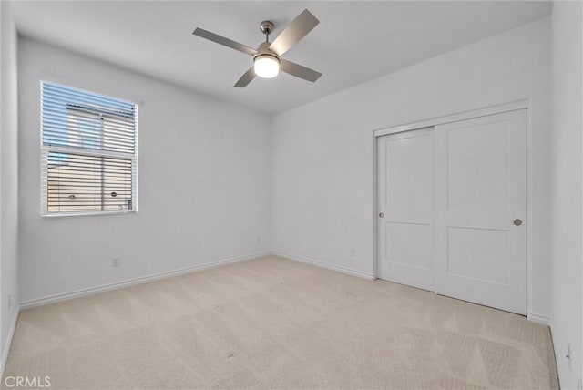 unfurnished bedroom with light colored carpet, ceiling fan, and a closet