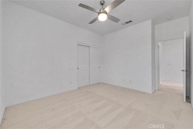 unfurnished bedroom featuring light colored carpet, ceiling fan, and a closet