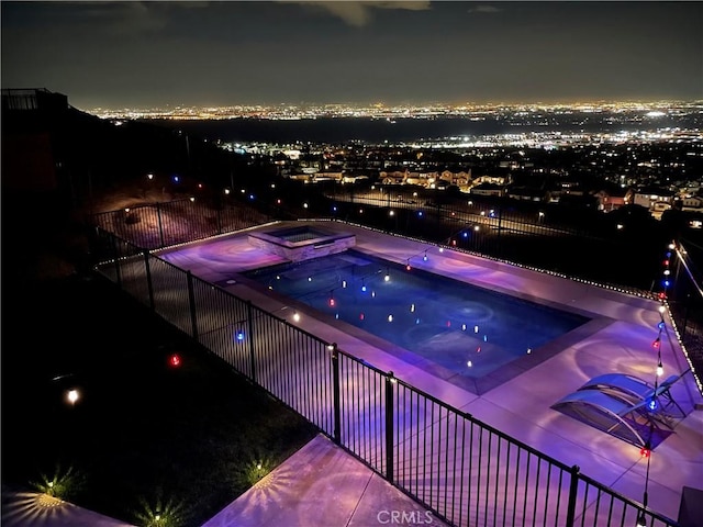 pool at twilight featuring an in ground hot tub