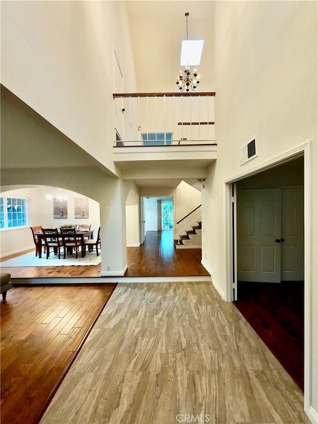 foyer featuring a towering ceiling, hardwood / wood-style floors, and a notable chandelier