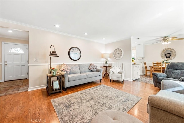 living room with light wood-type flooring, ceiling fan, and ornamental molding