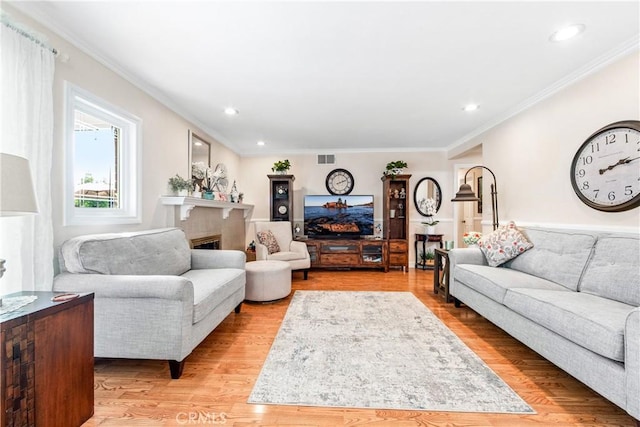 living room featuring ornamental molding, a tile fireplace, and light hardwood / wood-style floors