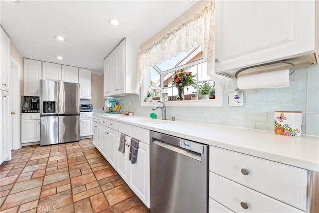 kitchen with white cabinets, stainless steel appliances, backsplash, and sink