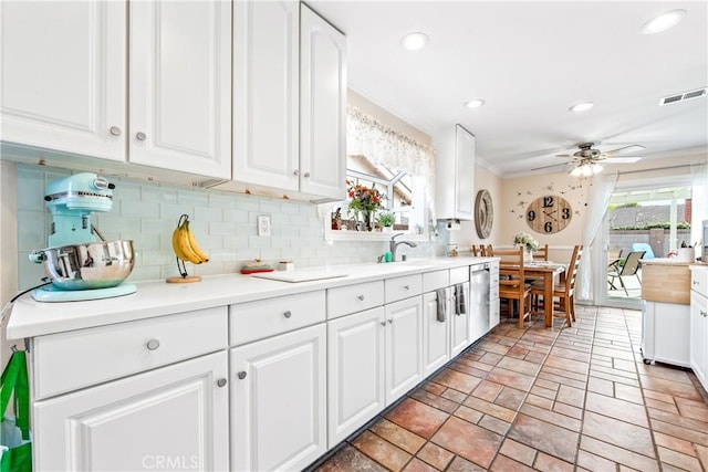 kitchen with stainless steel dishwasher, ceiling fan, white cabinets, crown molding, and decorative backsplash