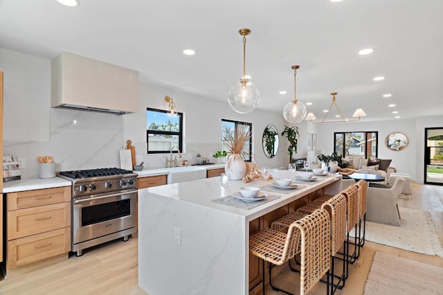 kitchen featuring a breakfast bar, decorative light fixtures, a center island, high end stainless steel range oven, and a healthy amount of sunlight