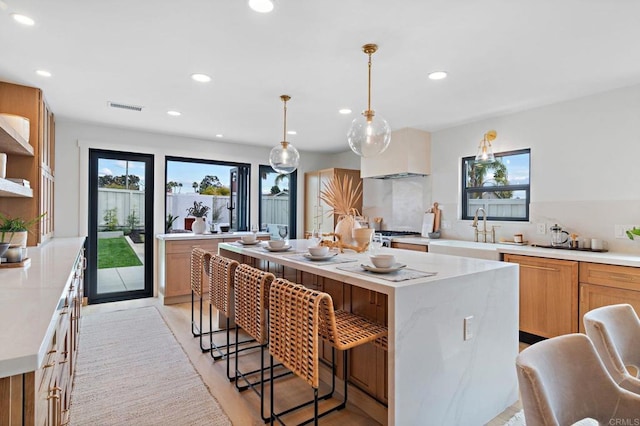 kitchen featuring pendant lighting, a kitchen bar, a center island, and sink