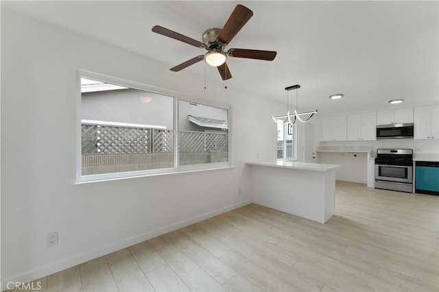 kitchen featuring white cabinets, hanging light fixtures, kitchen peninsula, stainless steel appliances, and light wood-type flooring