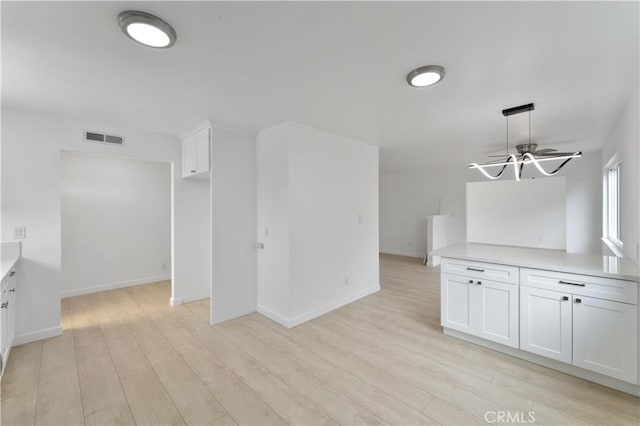 interior space with white cabinetry, light hardwood / wood-style flooring, and pendant lighting