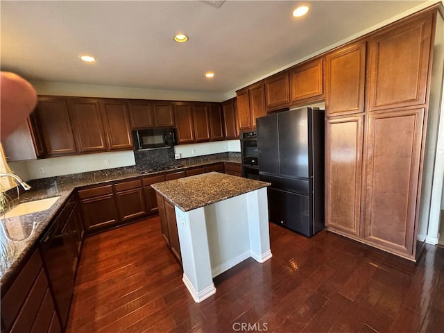 kitchen featuring dark stone countertops, dark hardwood / wood-style flooring, sink, and black appliances