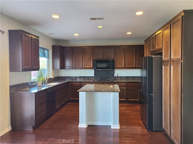 kitchen with sink, dark stone counters, a center island, black appliances, and dark wood-type flooring