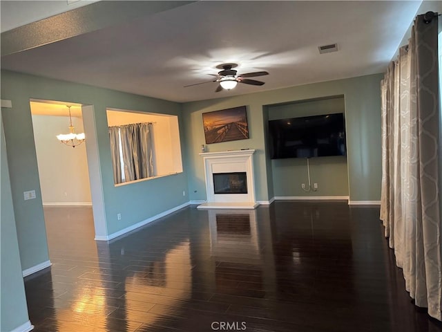 living room featuring ceiling fan with notable chandelier and dark hardwood / wood-style flooring