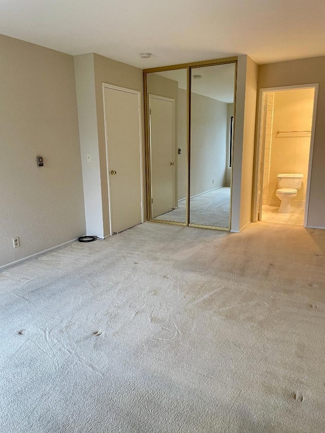 unfurnished bedroom with light colored carpet and ensuite bathroom