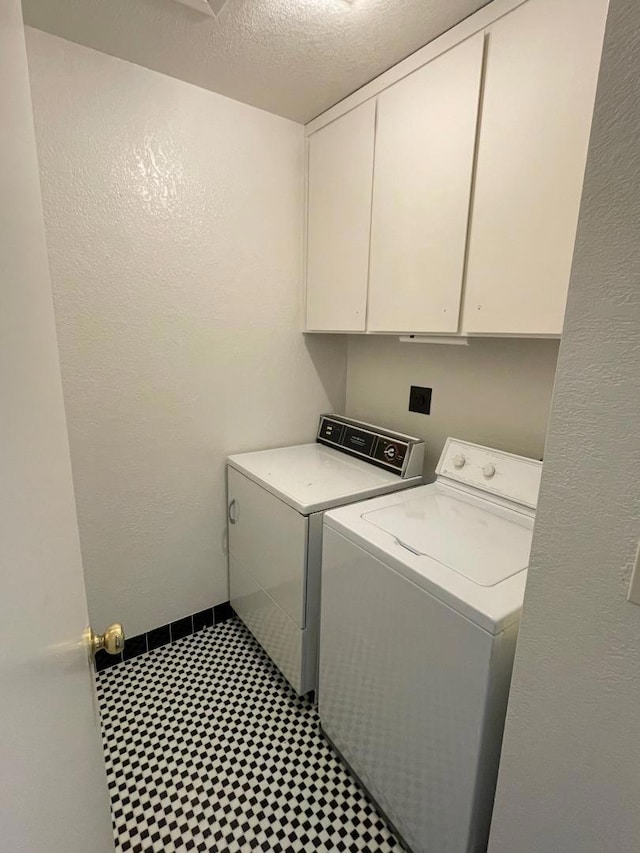 laundry room with cabinets, separate washer and dryer, and a textured ceiling