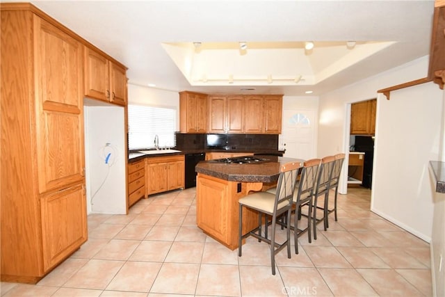 kitchen featuring a kitchen bar, sink, a center island, black dishwasher, and a raised ceiling