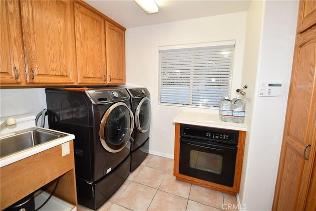 washroom featuring cabinets, sink, washer and dryer, and light tile patterned floors