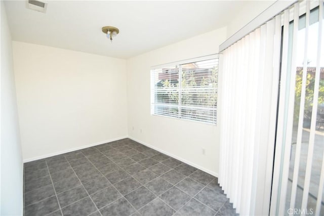 spare room featuring dark tile patterned floors