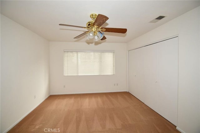 unfurnished bedroom featuring light carpet, a closet, and ceiling fan