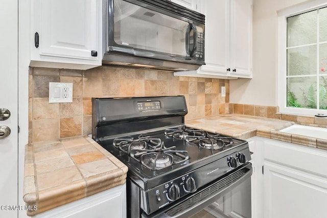 kitchen with sink, backsplash, black appliances, white cabinets, and tile countertops