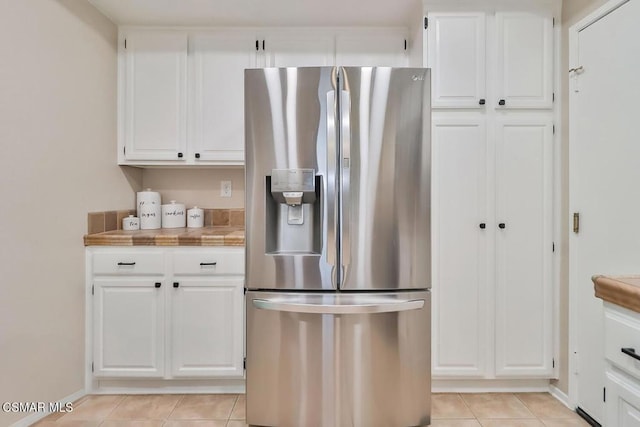 kitchen featuring light tile patterned flooring, tile countertops, white cabinets, and stainless steel fridge with ice dispenser