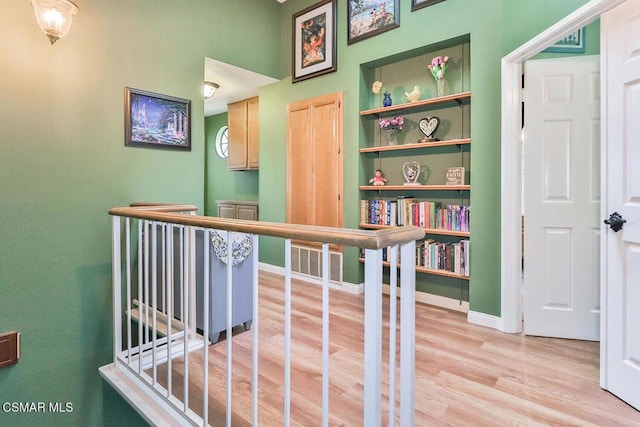 hall with built in shelves and light hardwood / wood-style floors