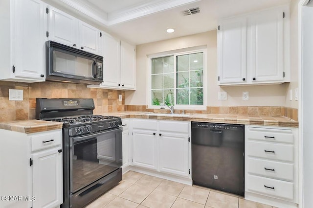 kitchen with sink, tile countertops, white cabinets, and black appliances