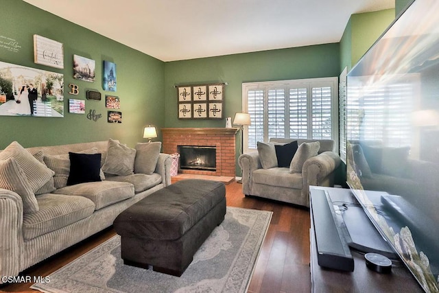 living room featuring a brick fireplace and dark hardwood / wood-style floors