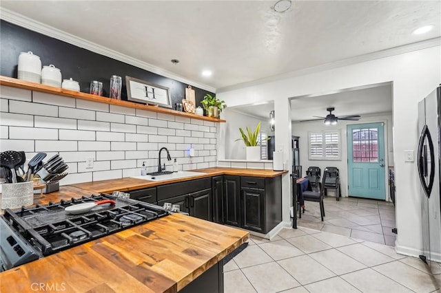 kitchen featuring cooktop, stainless steel fridge, butcher block counters, and sink