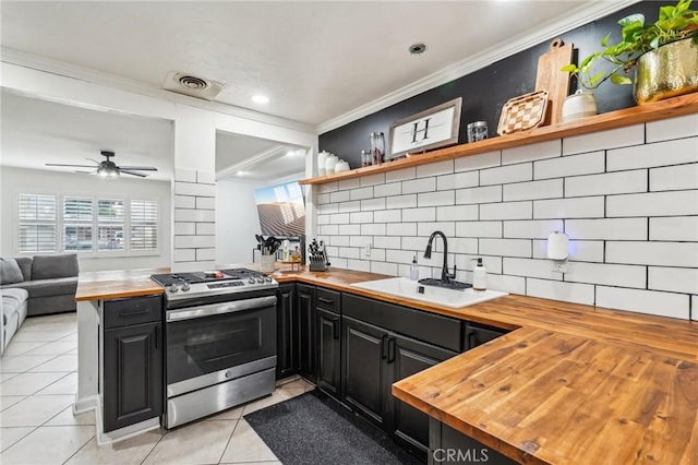 kitchen with stainless steel gas range oven, butcher block counters, sink, and crown molding