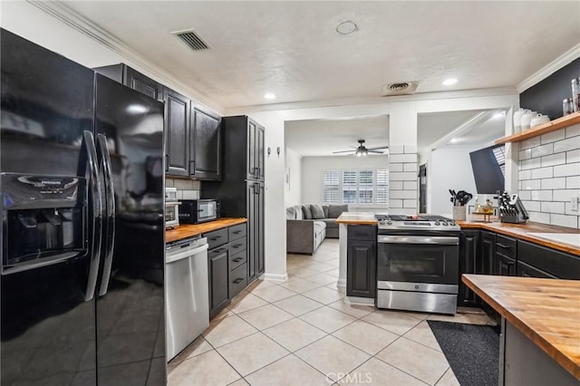 kitchen featuring light tile patterned floors, crown molding, wooden counters, tasteful backsplash, and black appliances