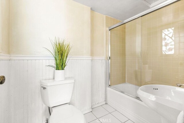 bathroom featuring enclosed tub / shower combo, tile patterned floors, and toilet