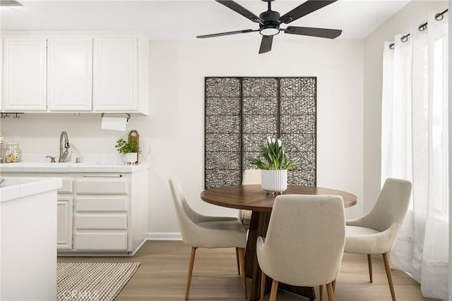 dining area with sink, light hardwood / wood-style flooring, and ceiling fan