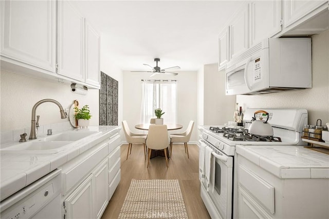 kitchen with white appliances, tile countertops, and white cabinets