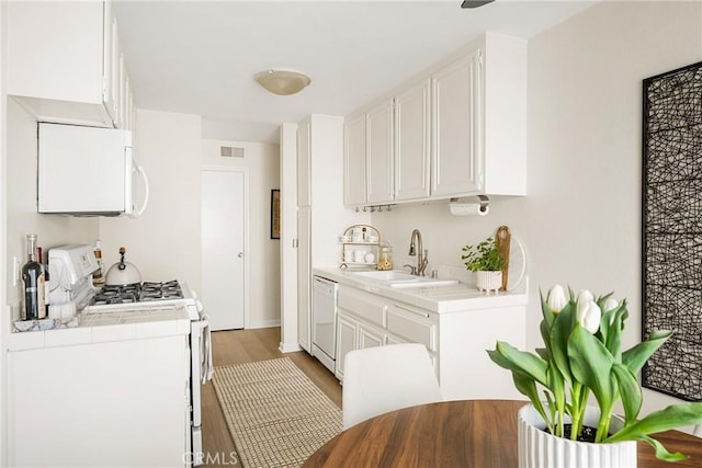 kitchen featuring white cabinetry, sink, white appliances, and light wood-type flooring