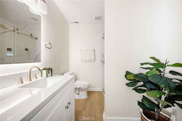 bathroom with wood-type flooring, toilet, vanity, and walk in shower