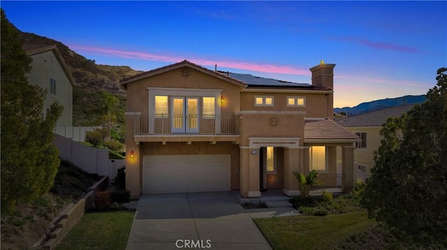 view of front of property featuring a mountain view, a garage, a balcony, and solar panels