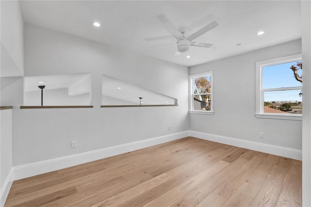 empty room featuring ceiling fan, a wealth of natural light, and light wood-type flooring