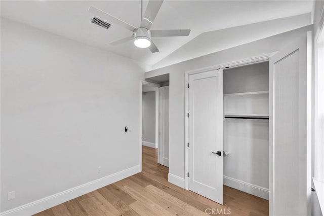 unfurnished bedroom featuring light hardwood / wood-style flooring, a closet, ceiling fan, and vaulted ceiling