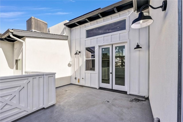 view of exterior entry with central AC and a patio area